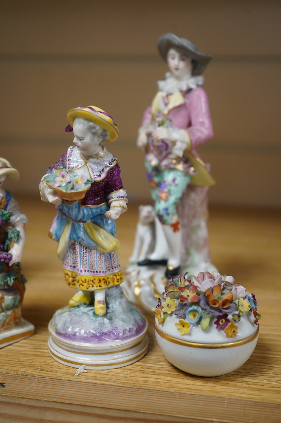 Eight various German porcelain figures, some with crossed sword marks to the bases and a floral encrusted pot and cover, largest 19cm high. Condition - fair, some losses